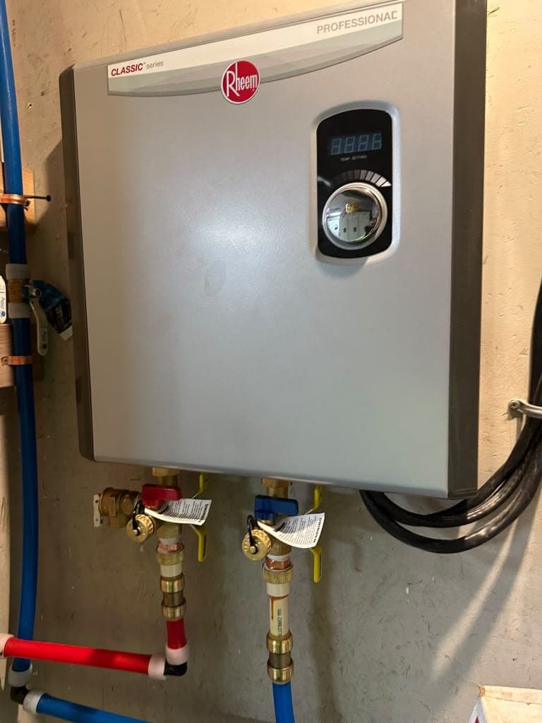 Wall-mounted electric tankless water heater with red and blue PEX lines