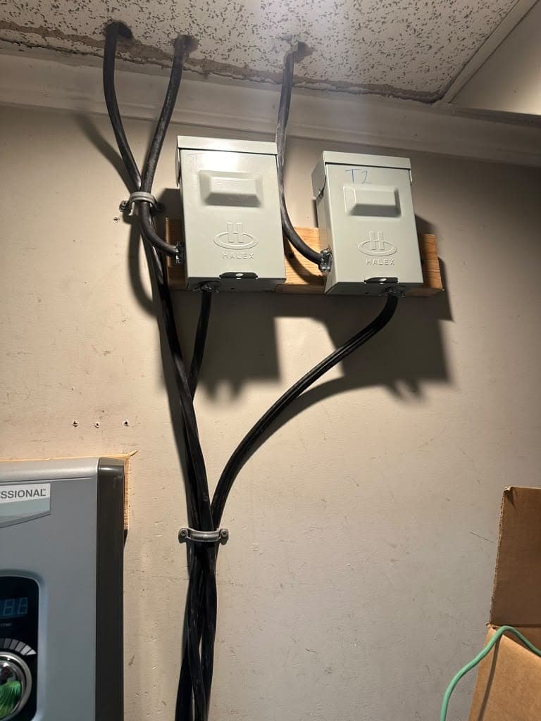 Two electrical safety disconnects mounted on a wall with routed cables