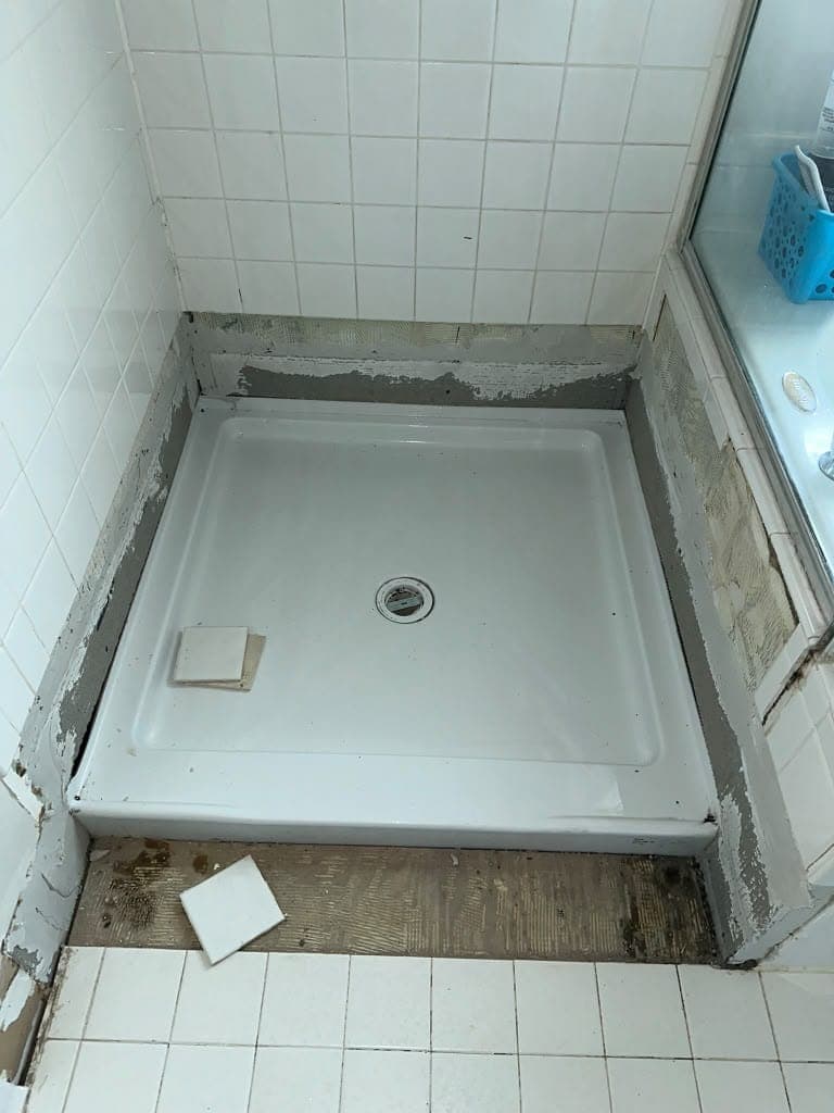 Shower area after repair: new white shower base installed
